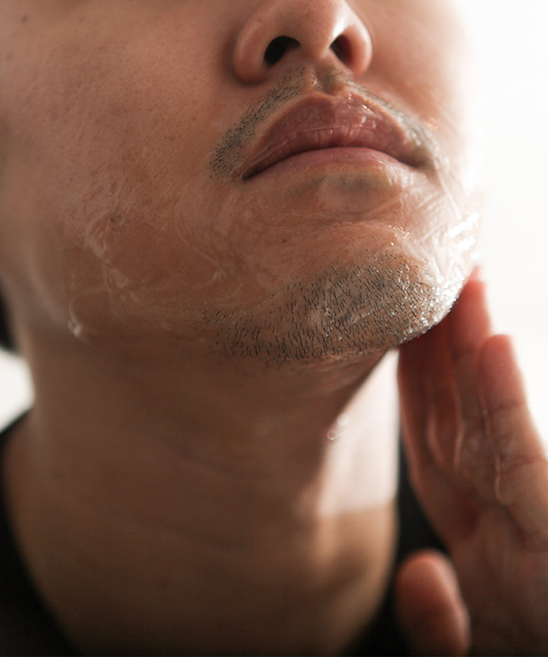 LAZY SOCIETY Cica Shaving Gel 2.3 50ml : homme se rase, gel aux soins à la main, gros plan visage.