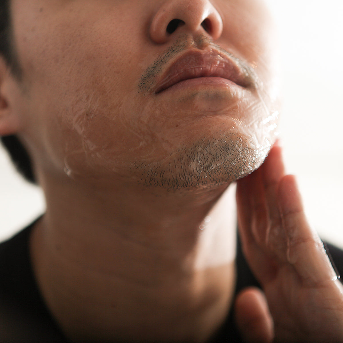 LAZY SOCIETY Cica Shaving Gel 2.3 50ml : homme se rase, gel aux soins à la main, gros plan visage.