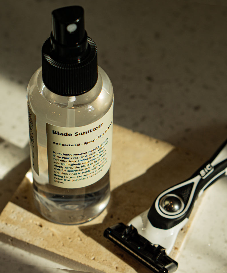 LAZY SOCIETY Razor Blade Sanitizer 120ml, spray désinfectant pour lame, bouteille noire sur lavabo avec rasoir, contexte salle d’eau