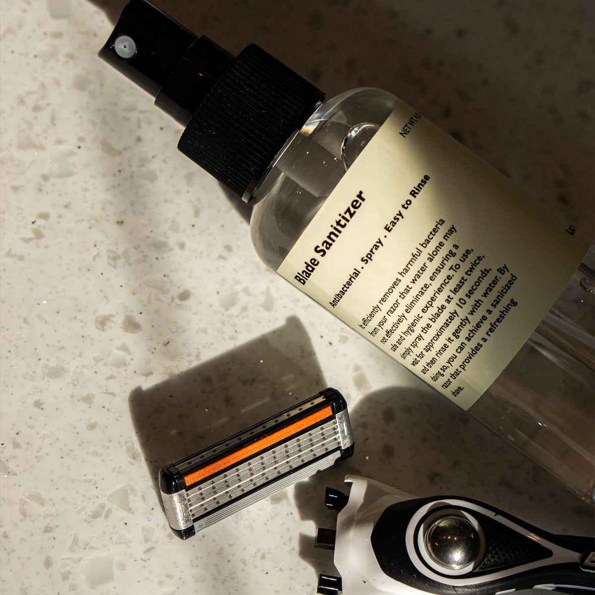LAZY SOCIETY Razor Blade Sanitizer 120ml : spray sur rasoir, flacon de la marque sur évier en pierre.