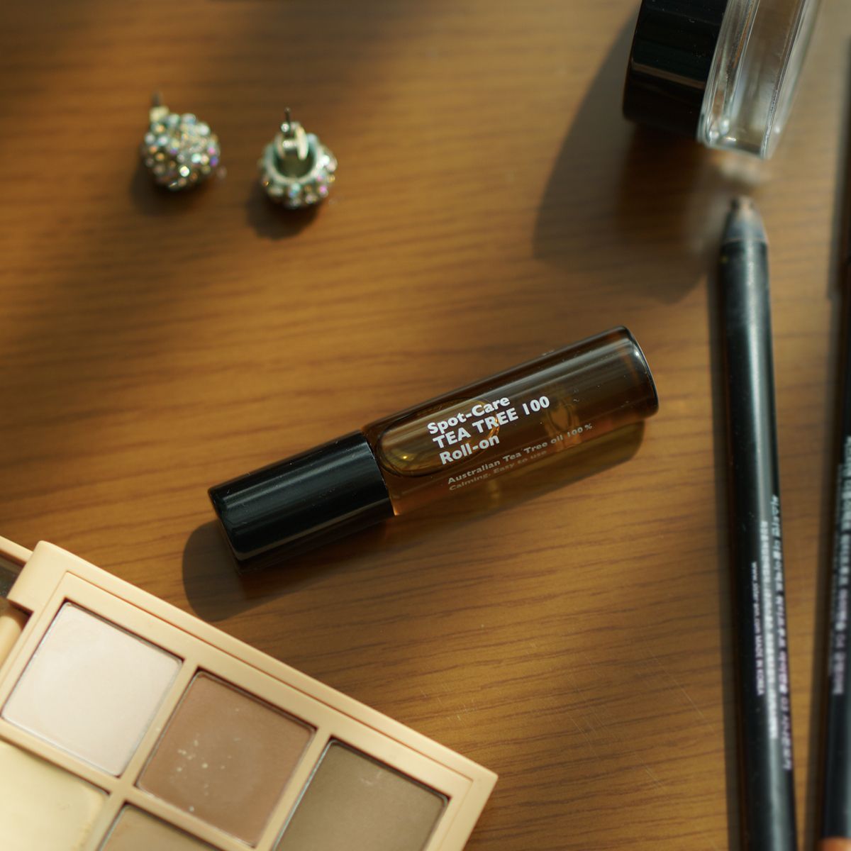 LAZY SOCIETY Spot Care Tea Tree 100 Roll on 5.5ml sur bureau, flacon roll-on près maquillage; marque en évidence.