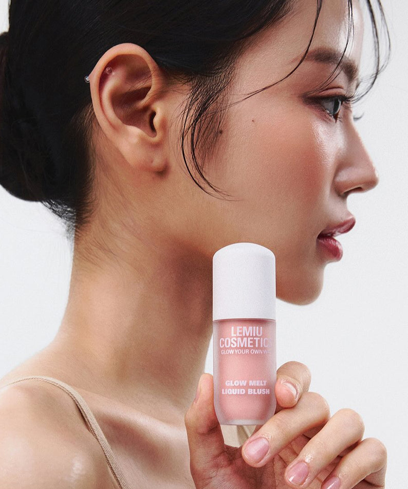 Femme tenant un flacon de LEMIU Glow Melt Liquid Blush, maquillage liquide brillant sur fond blanc.