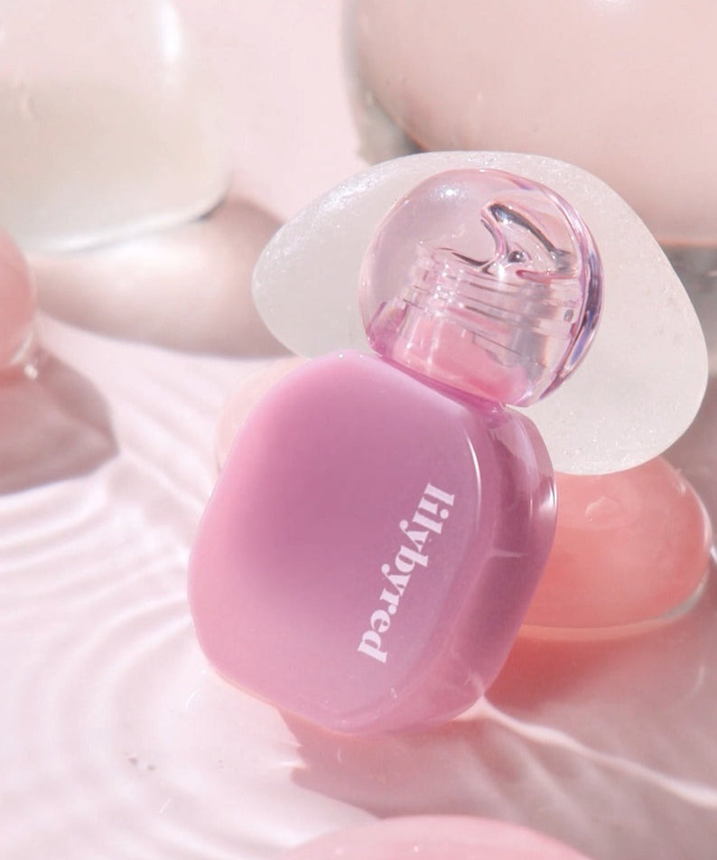 LILYBYRED Balming Dewy Tint de la marque LILYBYRED, flacon violet sur fond rose, gros plan lumineux