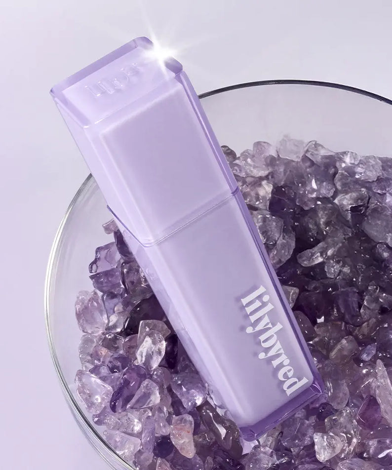 LILYBYRED Bloody Coating Tint de la marque sur fond lilas, flacon violet transparent devant des cristaux.