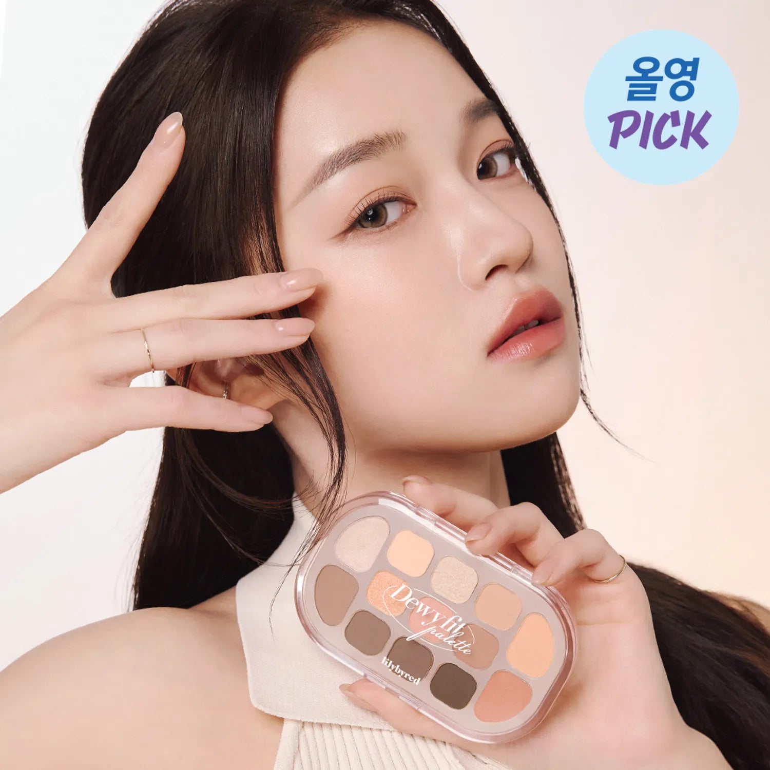 Décris l'image en français : LILYBYRED Dewy Fit Palette, maquillage délavé sur une femme tenant la palette, fond clair.