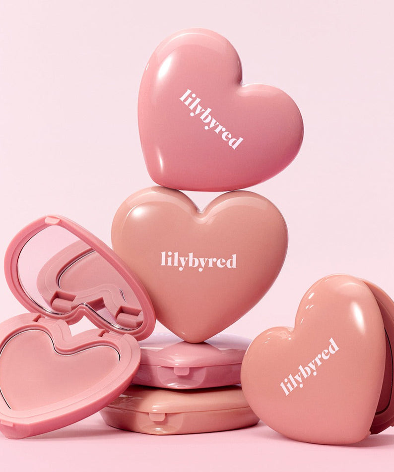 LILYBYRED Love Beam Cheek Balm de la marque LILYBYRED, packaging en forme de cœurs roses sur fond rose pastel.