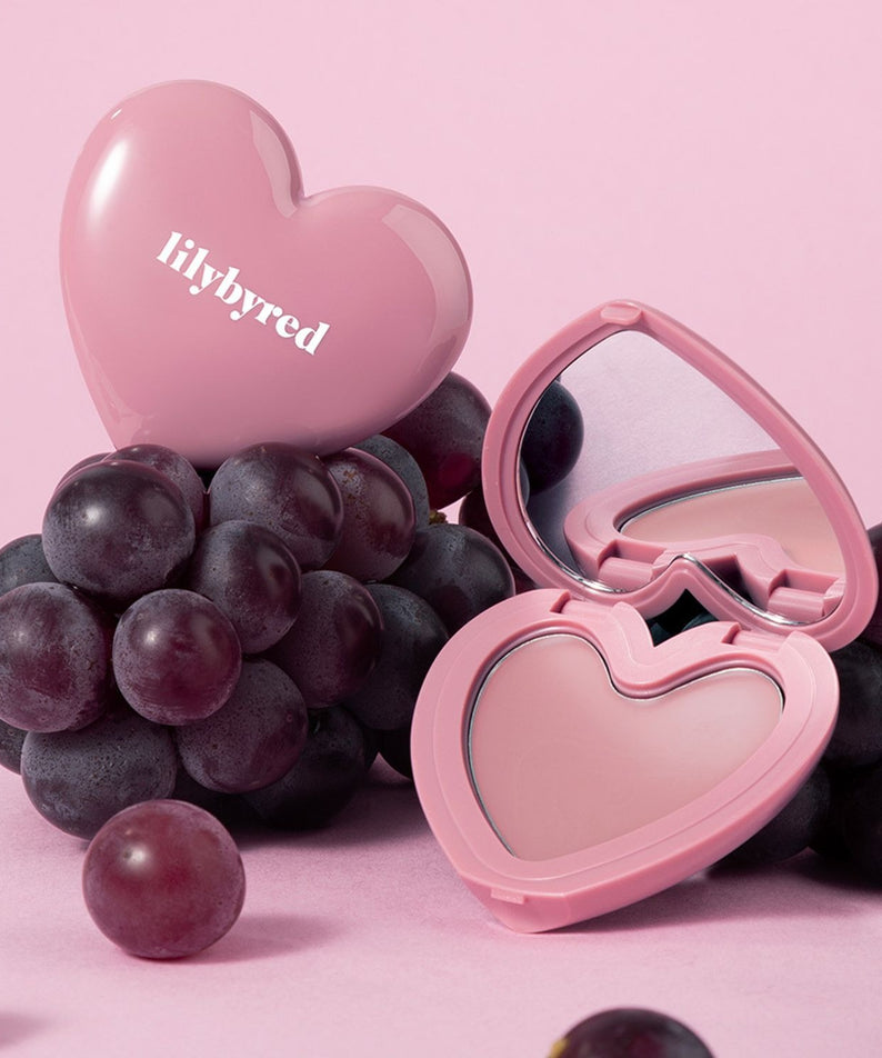 LILYBYRED Love Beam Cheek Balm de la marque LILYBYRED, présenté en forme de cœur rose sur fond rose avec raisins