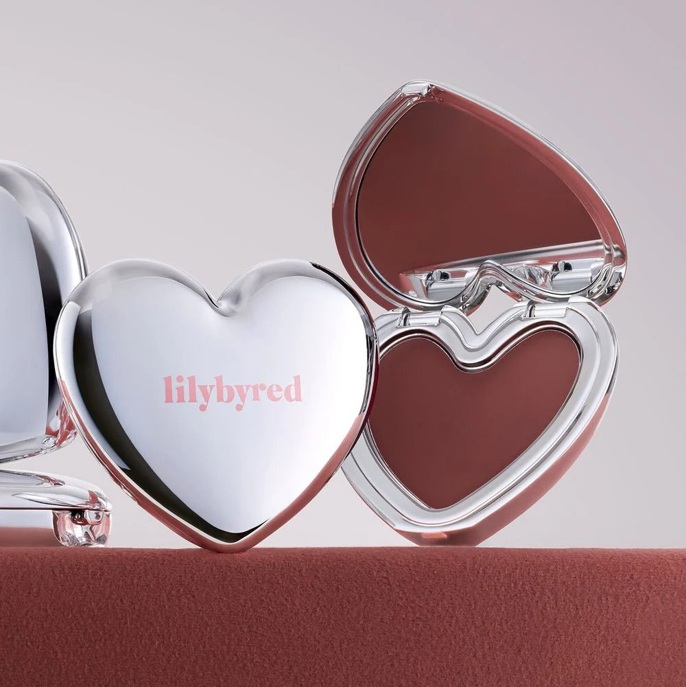 LILYBYRED Love Beam Cheek Mousse, marque lilybyred, packaging cœur argenté sur fond rose, maquillage blush.