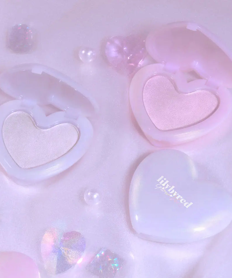 LILYBYRED Love Beam Glow Veil, marque LILYBYRED : éclats de lumière, coeurs brillants sur fond rose pastel, maquillage