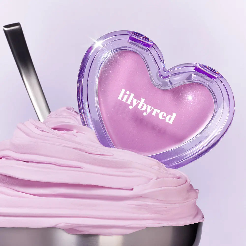 Décris l'image en français : LILYBYRED Love Beam Sherbet Cheek, marque LILYBYRED, flacon cœur violet sur fond pastel, maquillage