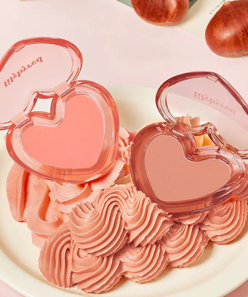 LILYBYRED Love Beam Sherbet Cheek de la marque LILYBYRED, en coffret cœur rose, sur plateau crème, avec gourmandises décoratives.