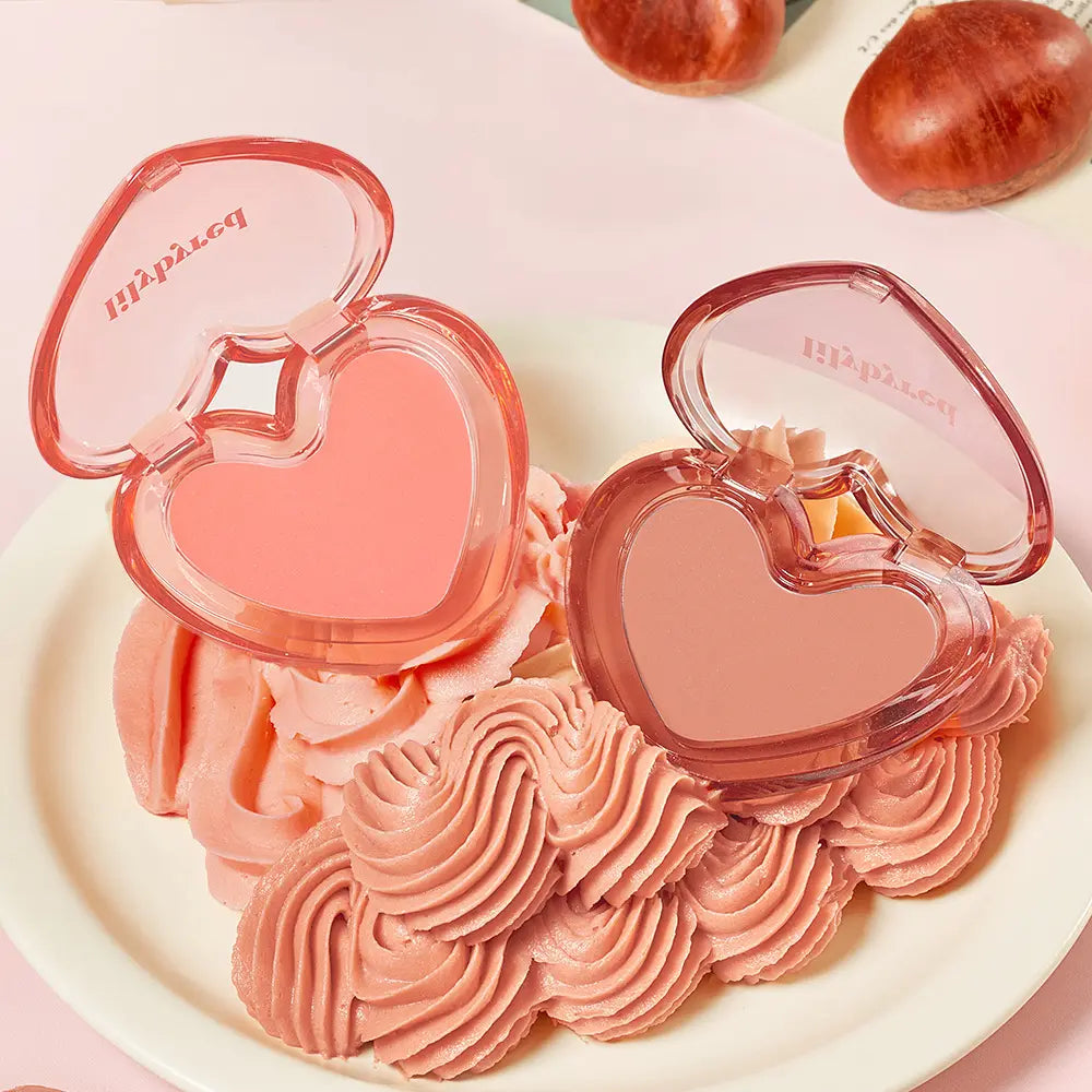 LILYBYRED Love Beam Sherbet Cheek de la marque LILYBYRED, en coffret cœur rose, sur plateau crème, avec gourmandises décoratives.