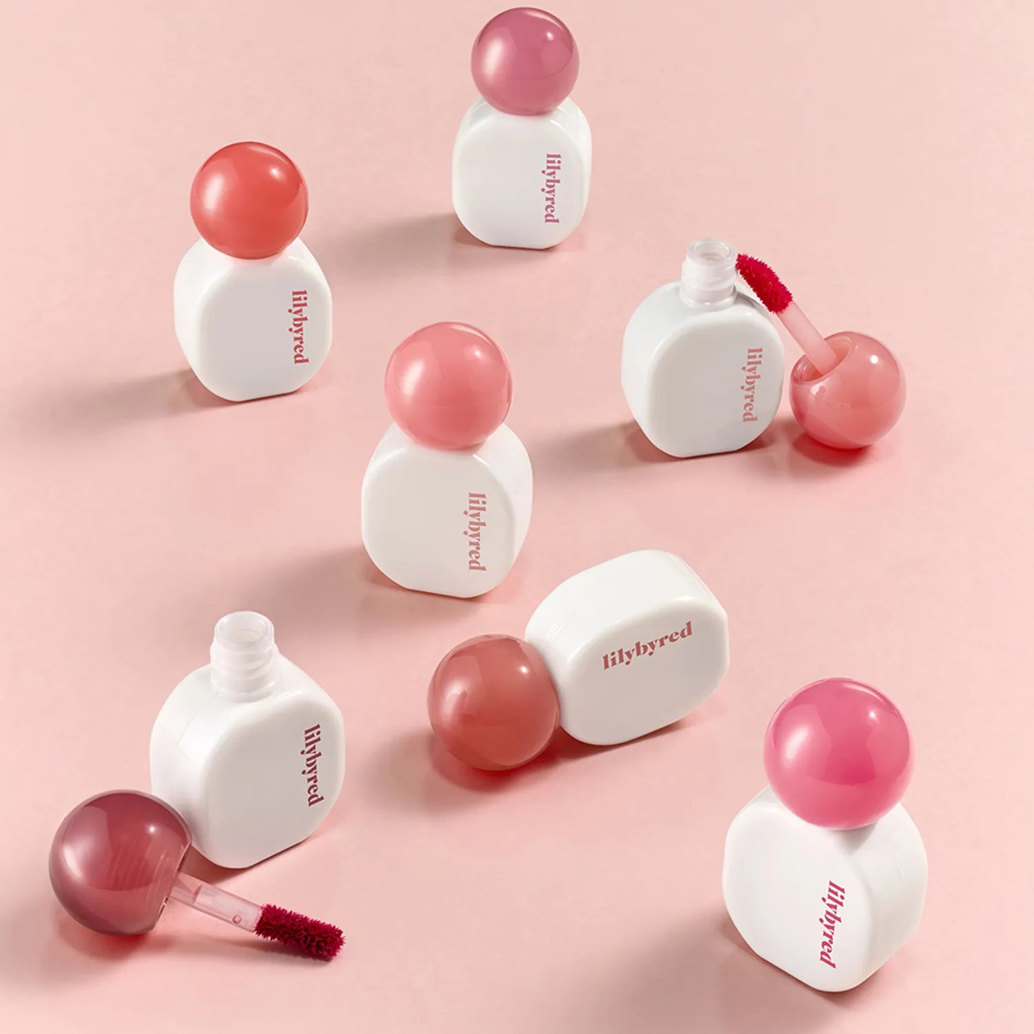 LILYBYRED Sugar Wrapping Tint Gloss de la marque LILYBYRED, gloss teinté rose sur fond rose pastel, packshots.