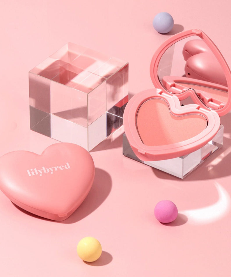 Maquillage romantique LILYBYRED Love Beam Cheek en forme de cœur sur fond rose, idéal pour une touche de couleur douce.
