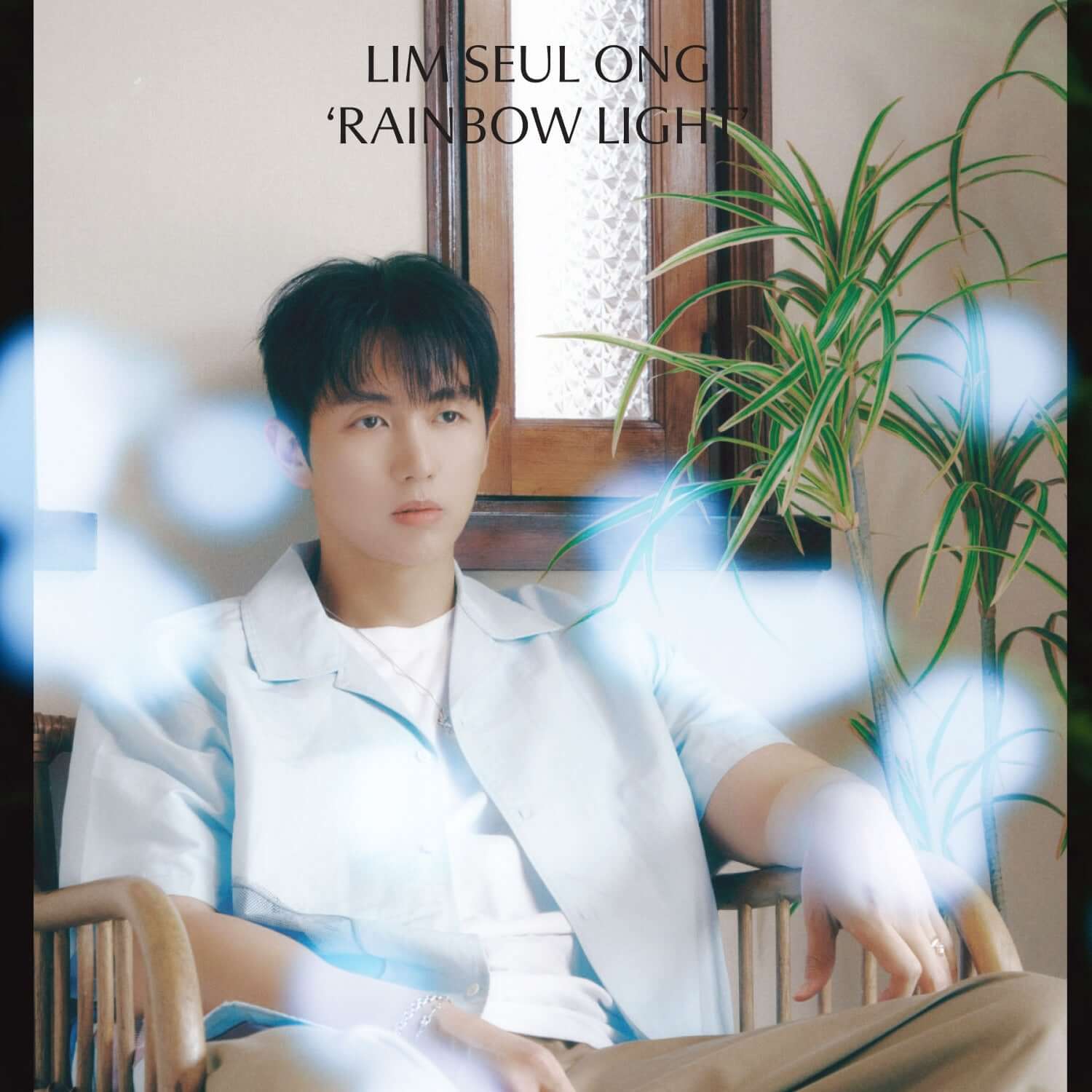 LIM SEULONG - [Rainbow Light] - Album Kpop : photo de LIM SEULONG assis, intérieur lumineux, ambiance arc-en-ciel