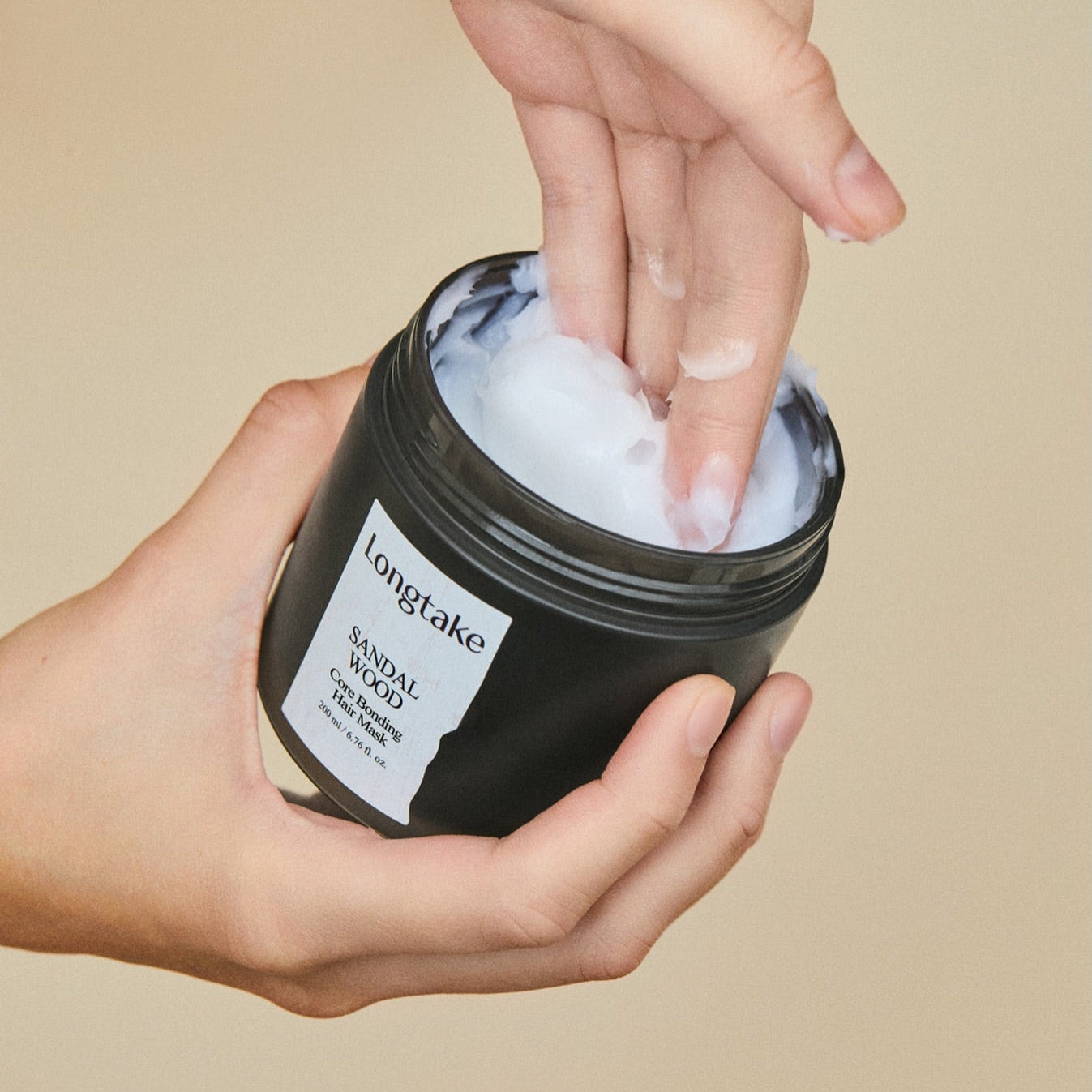 LONGTAKE Core Bonding Perfume Hair Mask Hair Pack 200ml, pot noir sur mains, texture crème blanche, ambiance beige.