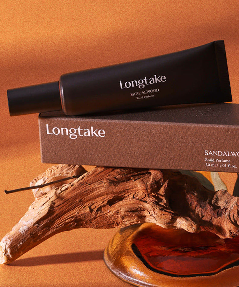 LONGTAKE Solid Perfume 30ml en stick sur fond beige, flacon Longtake et bois de santal en contexte visuel