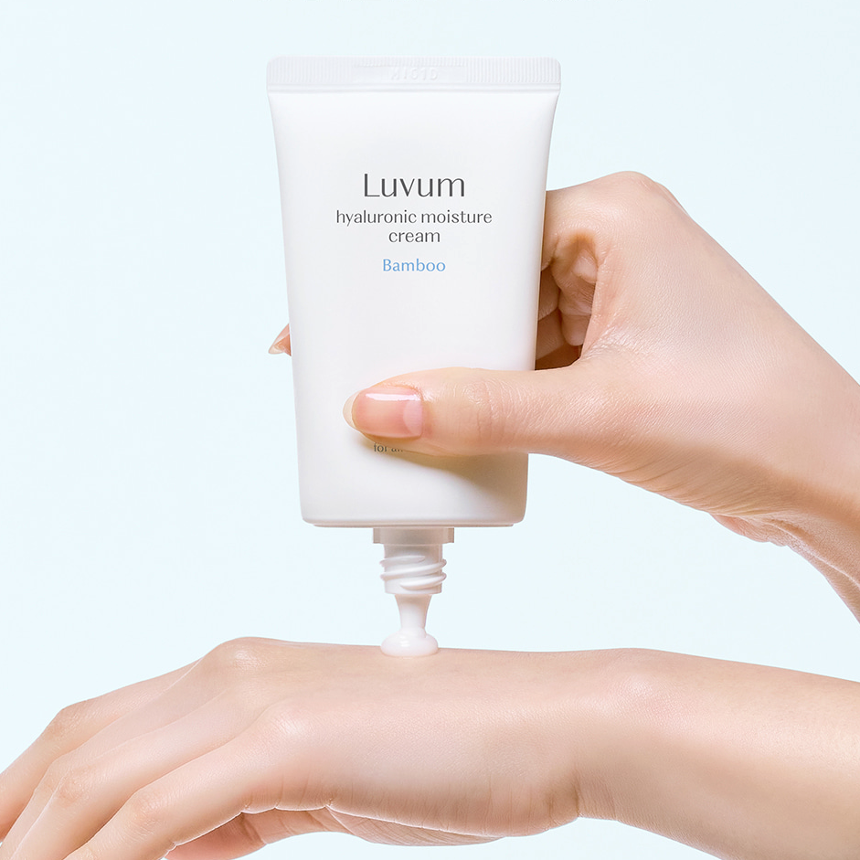 LUVUM Bamboo Hyaluronic Acid Moisture Cream 70ml, tube crème sur peau, main appliquant, fond clair lumineux.