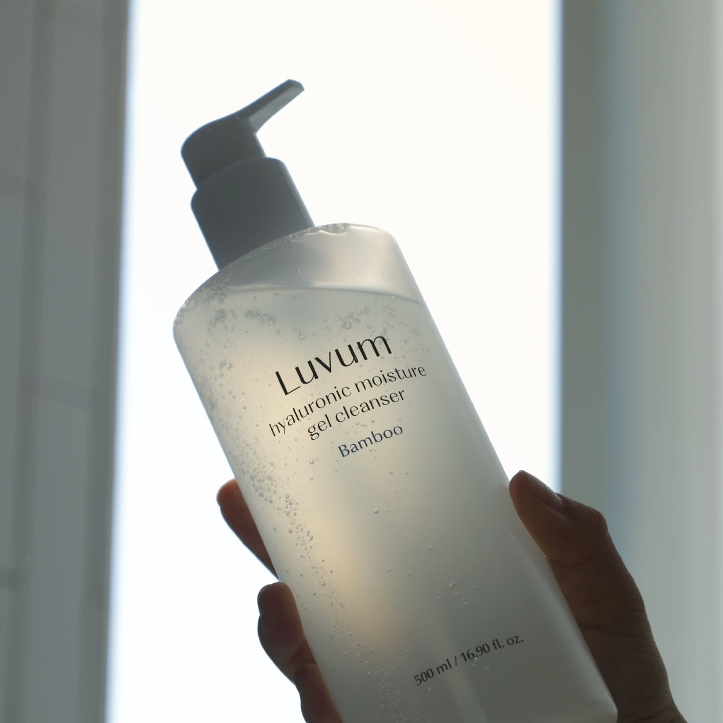 LUVUM Bamboo Hyaluronic Acid Moisture Gel Cleanser 200ml, flacon devant fond lumineux, main tenant le produit Luvum.