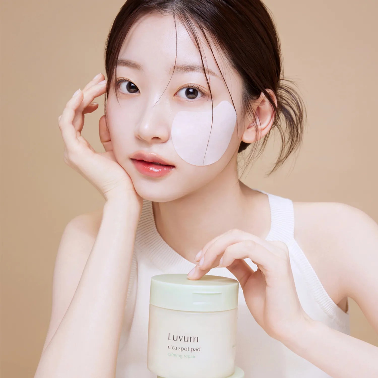 LUVUM Calming Repair Cica Spot 60 Pads, la marque Luvum sur pot cosmétique, jeune femme applique un patch visage