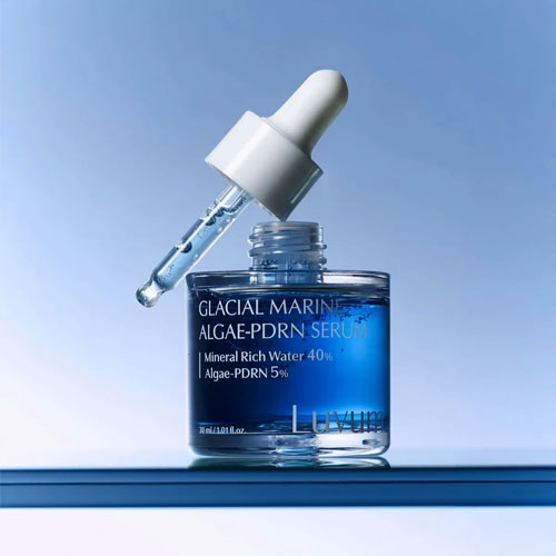 Décris l'image en français : LUVUM Glacial Marine Aigae-PDRN Serum 30ml en flacon bleu, décor glace et eau, sur fond clair.