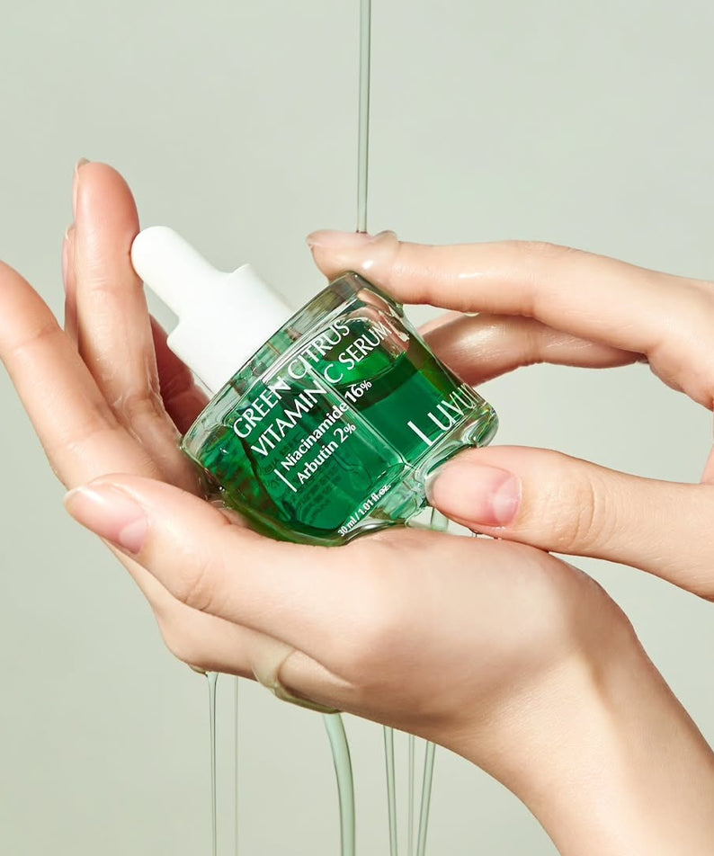 LUVUM Green Citrus Vitamin C Serum Plus 30ml de la marque LUVUM, flacon vert en mains, contexte salle de bain.