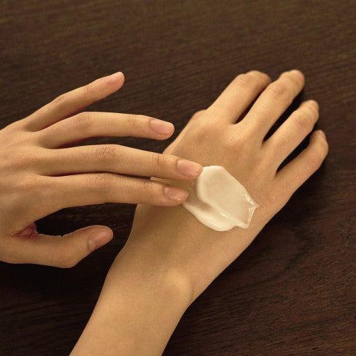 LUVUM Green Wood Perfume Hand Cream 50ml, crème parfumée sur mains, marque LUVUM, texture sur fond bois foncé.