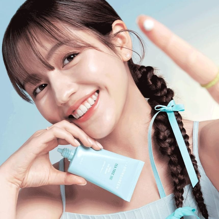 BRINGGREEN Teatree Cica Fresh Sun Cream 50ml, tube de crème sur une jeune femme au soleil, fond bleu.