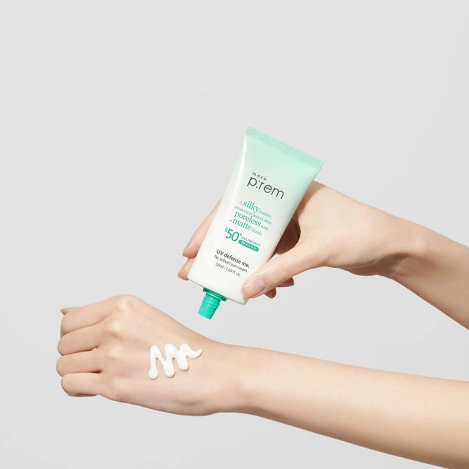 Main appliquant MAKE P:REM UV Defense Me No-Sebum Sunscreen 50ml, peau avec trace UV, fond clair, marque P:rem