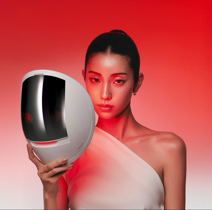 MAKEON Onface LED Mask de la marque, masque LED sur fond rouge, portrait beauté avec modèle en studio.