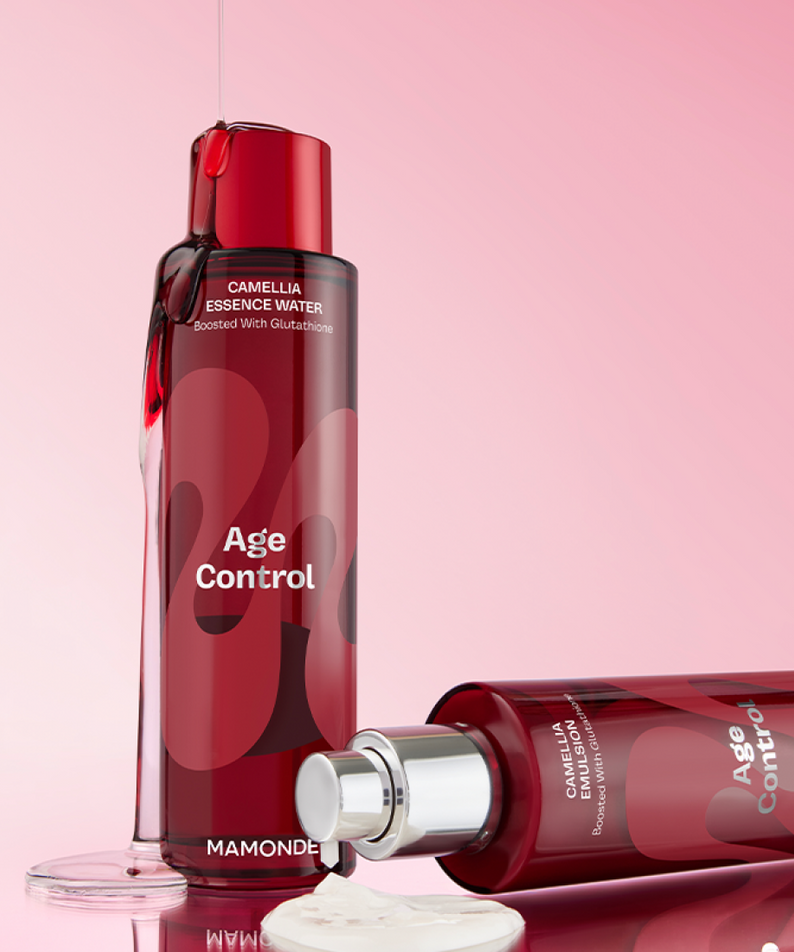 Bouteilles de MAMONDE Age Control Camellia Essence Water 150ml sur fond rose, essence renversée et capuchon ouvert.