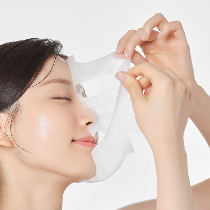 Décris l'image en français : MAMONDE Flora Glow Rose Ampoule Mask Pack, femme appliquant le masque tissu, ambiance skincare.