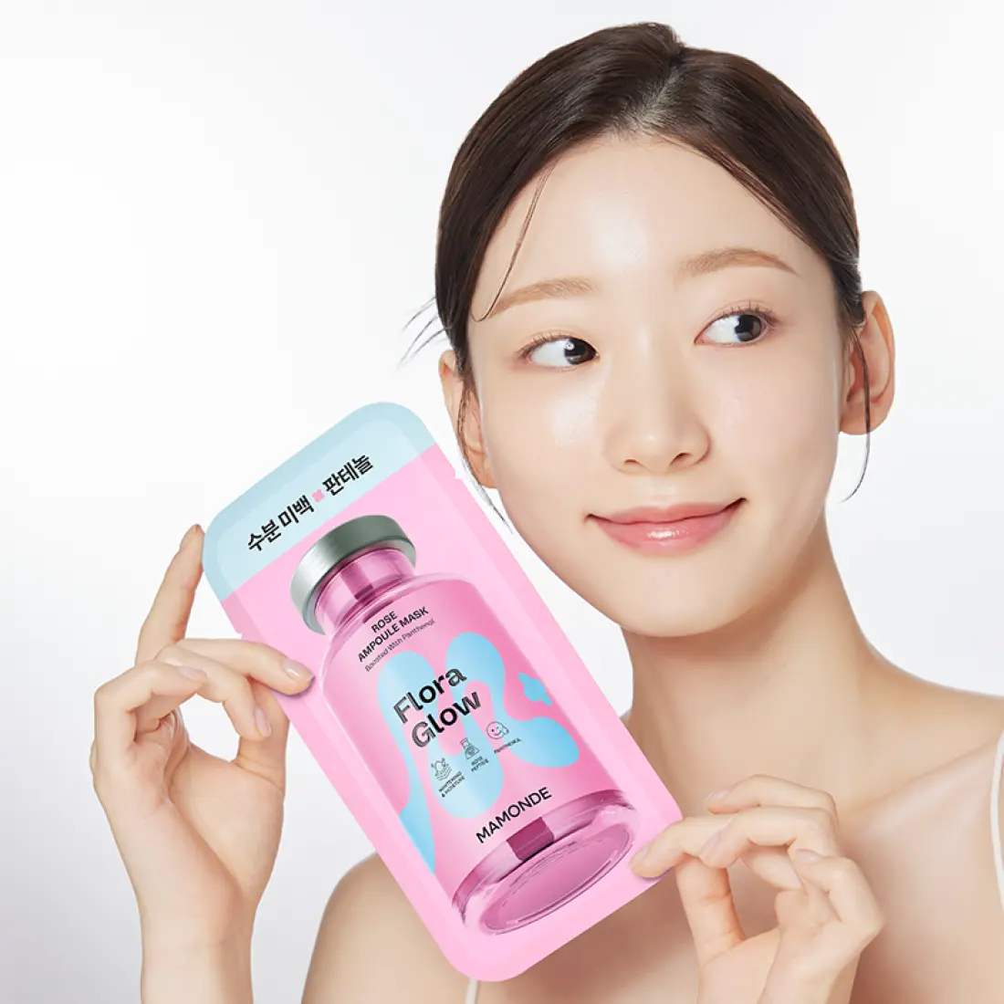Décris l'image en français : MAMONDE Flora Glow Rose Ampoule Mask Pack, la marque, sur une femme, visage et masque rose.