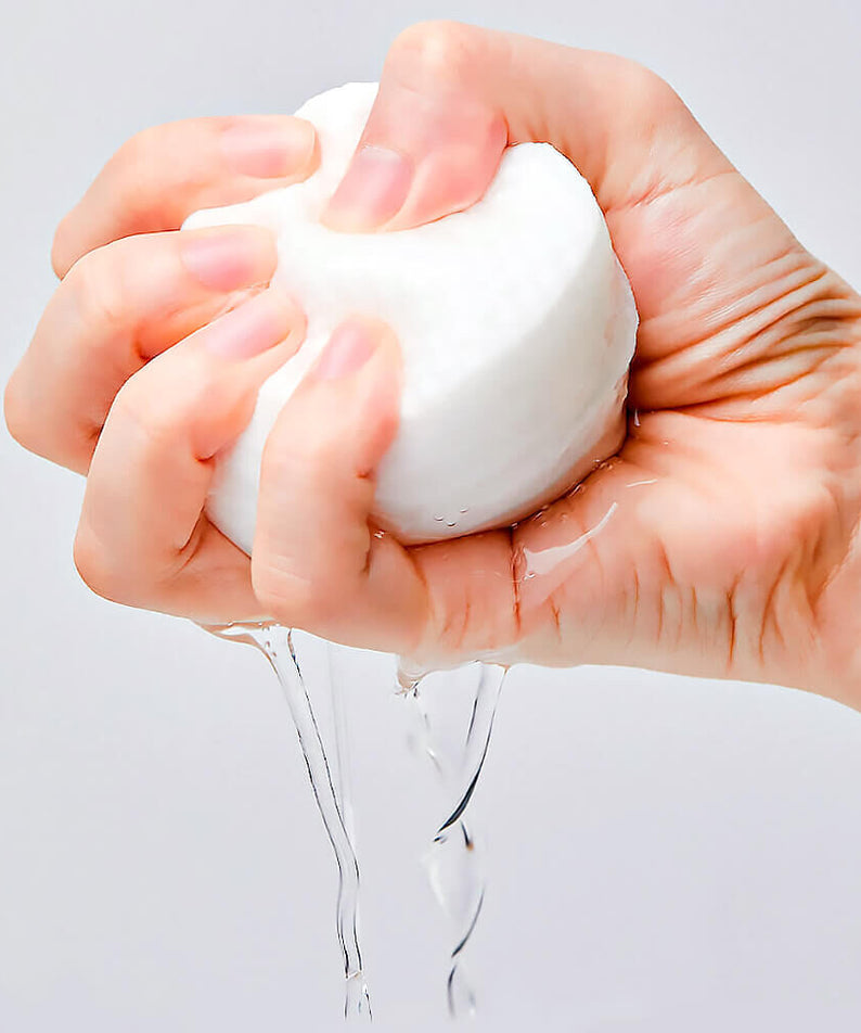 Main tenant un tampon de coton humide, représentatif des MANYO Galactomy Clear Skin Pads 60 sheets pour un soin de la peau efficace.