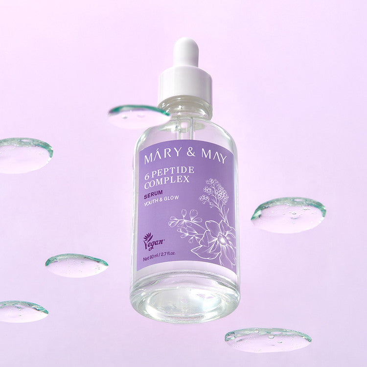 MARY&MAY 6 Peptide Complex Serum 80ml, flacon sur fond rose avec gouttes et pétales, ambiance beauté