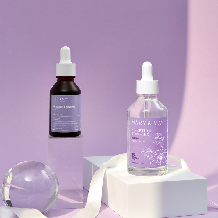 MARY&MAY 6 Peptide Complex Serum 80ml : bouteilles sur socle blanc, fond violet, marque MARY&MAY en mise en scène beauté