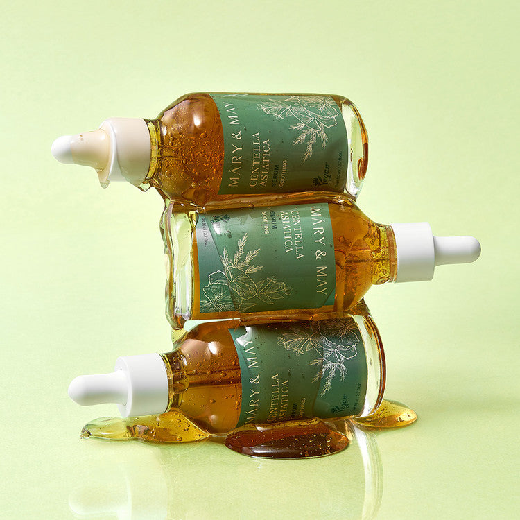Décris l'image en français : MARY&MAY Herbal Extract Serum 80ml, bouteilles ambrées vertes sur fond vert pastel.