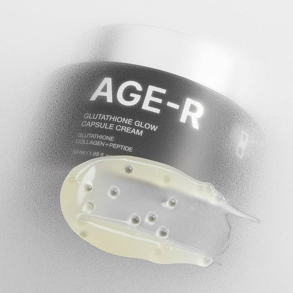 Décris l'image en français : MEDICUBE AgeR Glutathione Glow Capsule Cream, tube noir et texture crème sur fond clair.