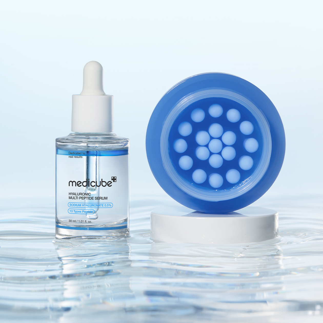MEDICUBE Hyaluronic Moisturizing Capsule Cream 55g : sérum flacon et capsule bleue sur fond bleu, gouttes d’eau, marque MEDICUBE