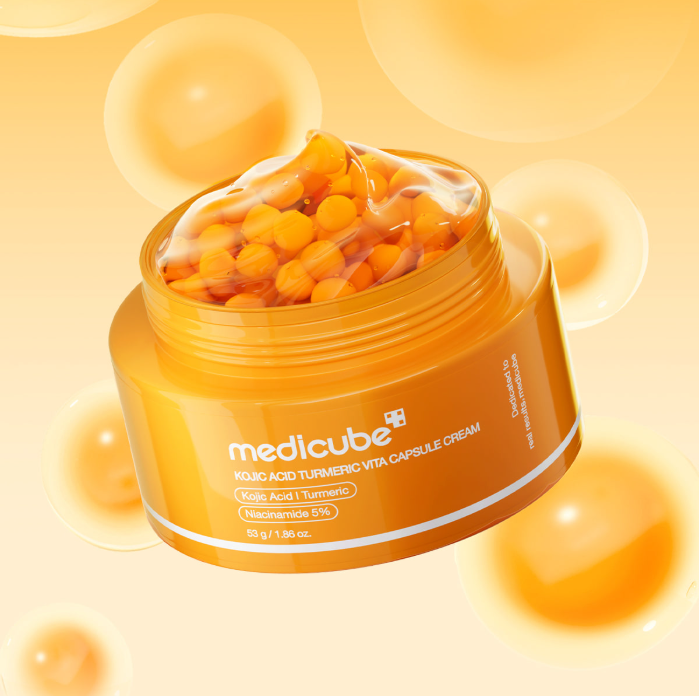 MEDICUBE Kojic Acid Turmeric Vita Capsule Cream 53g : pot crème sur fond jaune avec capsules de vitamine, ambiance cosmétique
