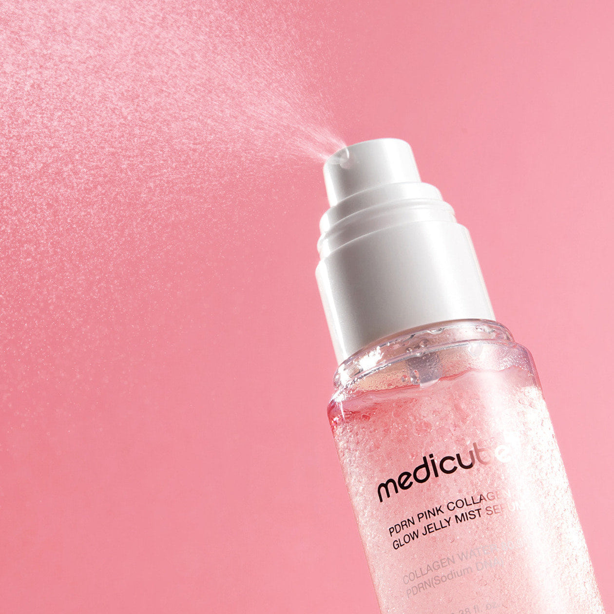 MEDICUBE PDRN Pink Collagen Jelly Mist Serum 100ml de Medicube, flacon rose sur fond rose scintillant, gouttes visibles