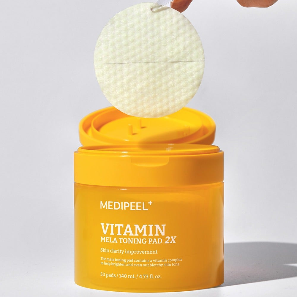 MEDIPEEL Vitamin Mela Toning Pads 2X 140ml 50sheets, flacon jaune avec pad tenu, contexte beauté, photo produit