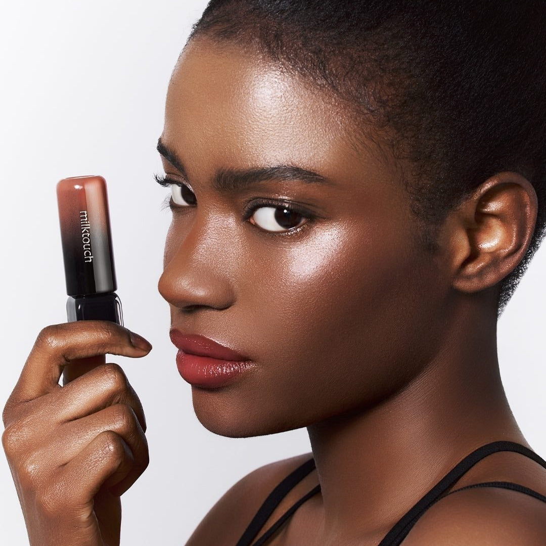 MILK TOUCH Black Peel-Off Lip Tattoo, femme applique le produit; lip art noir, marque MILK TOUCH, fond blanc, gros plan visage.