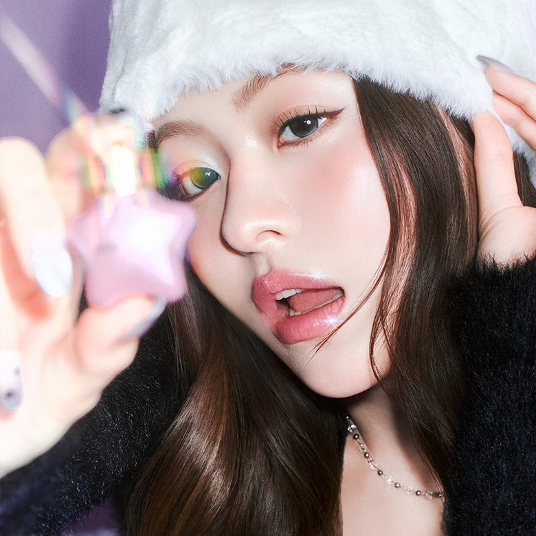 MILK TOUCH Ornament Prism Shine Pearl Gloss : maquillage nacré prismatique sur une femme près d’une décoration étoile, fond doux