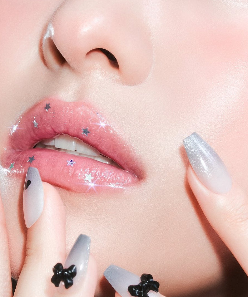 MILK TOUCH Ornament Prism Shine Pearl Gloss, gloss nacré en finition prisme sur lèvres maquillées, décors étoiles, gros plan.