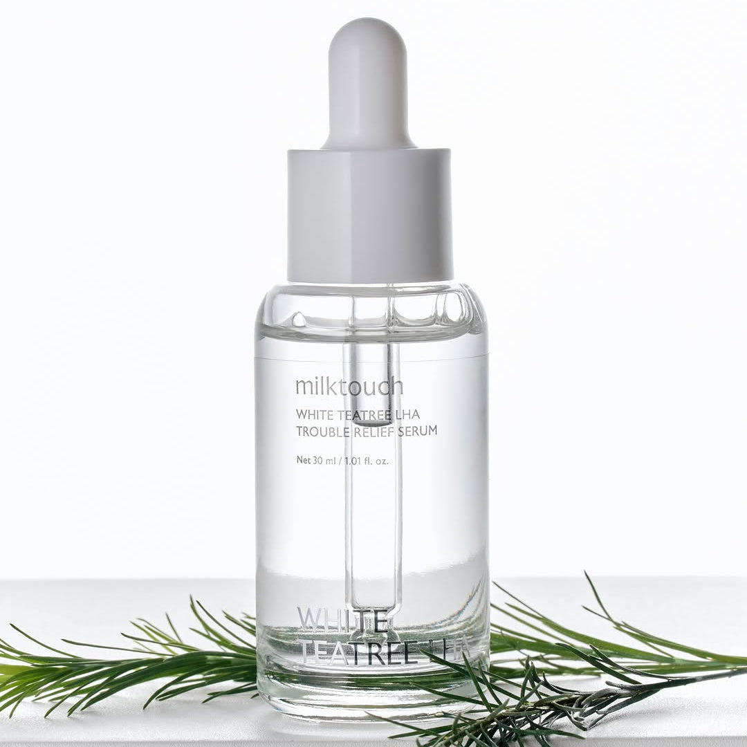 MILK TOUCH White Tea Tree Laha Trouble Relief Serum 30ml sur fond blanc avec théier, bouteille et pipette, marque visible.