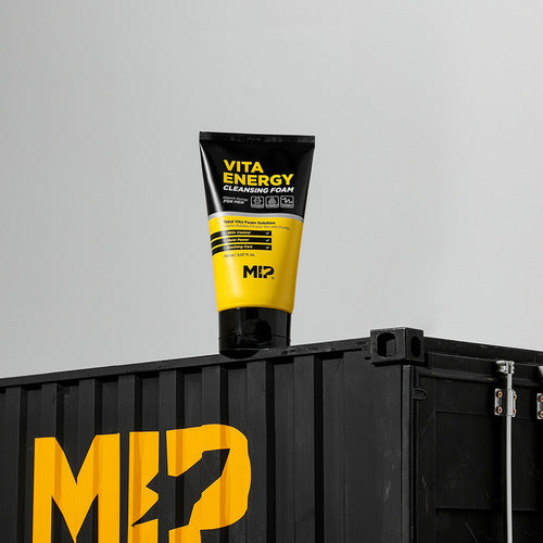 Décris l'image en français : MIP Minam Cream Tone-up Whitening + Vita Energy Foam Cleansing, tube Vita Energy sur support noir.