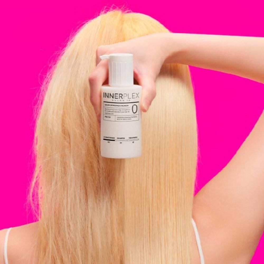 MISE EN SCENE Innerplex Hair Strengthener 145g Plan : femme tient le flacon INNЕРPLEX, fond rose, application sur cheveux