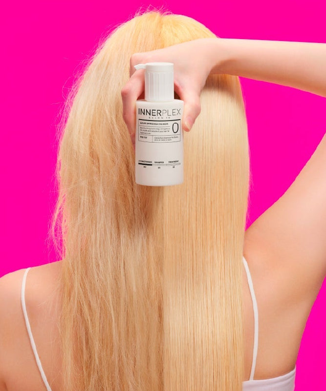 MISE EN SCENE Innerplex Hair Strengthening Shampoo 375g : flacon sur cheveux blonds, tenue par une main, fond rose.