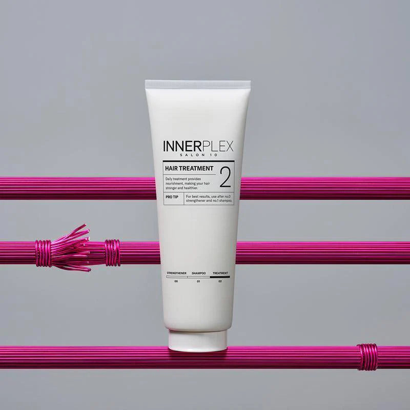 MISE EN SCENE Innerplex Hair Strengthening Treatment 240g en tube blanc sur fond gris avec rubans violets et mèches.